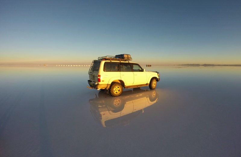 Jeep no Salar de Uyuni alagado durante o nascer do sol, Bolívia